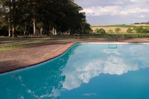una piscina con reflejo del cielo en el agua en Estancia Ave María en Tandil