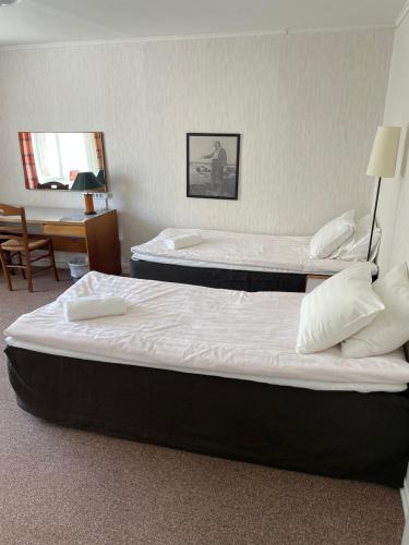 two beds in a hotel room with a desk at Utoopia Külalistemaja Viscosas in Kõrgessaare