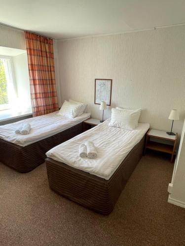 two beds in a hotel room with two lamps at Utoopia Külalistemaja Viscosas in Kõrgessaare