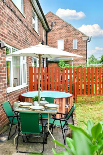 a table and chairs with an umbrella in a yard at A Luxurious Home with Hot Tub and Man Cave! 9ppl in Whiston