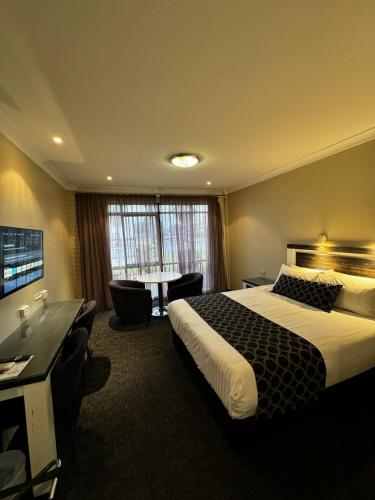 a hotel room with a large bed and a desk at Acacia Motel in Griffith