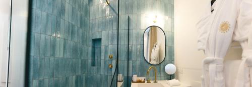 bagno con parete piastrellata blu e specchio di Villa Lorenzo Chambres & Restaurant Barcelonnette Hotel a Barcelonnette