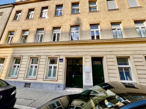 a building with green doors and windows on a street at Vienna Charm Apartments Landstraße in Vienna