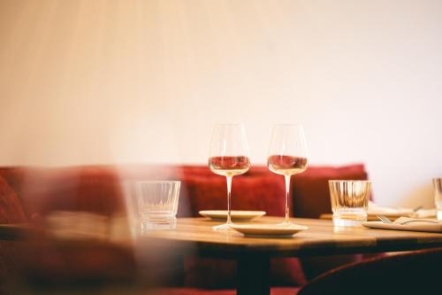 two glasses of wine sitting on a wooden table at Villa Lorenzo Chambres & Restaurant Barcelonnette Hotel in Barcelonnette