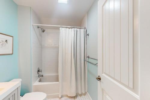 a white bathroom with a shower curtain and a toilet at Adventure Annapolis in Annapolis