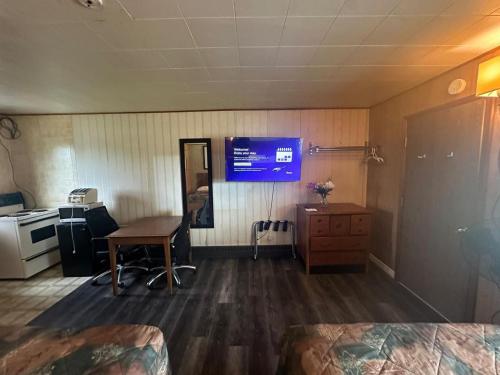 a room with a tv and a desk and a table at Pine Ridge Motel in Timmins