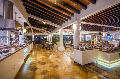 a restaurant with a buffet line with tables and chairs at Buenaventura Grand Hotel & Great Moments - All Inclusive in Puerto Vallarta