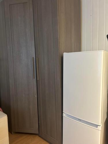 - un réfrigérateur blanc dans une cuisine avec des placards en bois dans l'établissement Idéal, à Vincennes