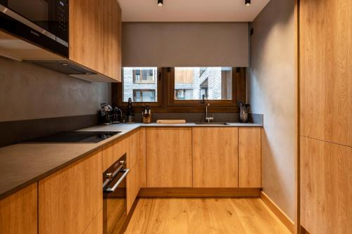 a kitchen with wooden cabinets and a sink and a window at Un diamante de montaña l A Pie De Pistas - Gimnasio - Sauna - Piscina l 8Pax l by BonesVacances in El Tarter