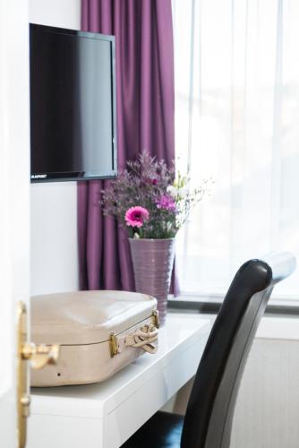 a suitcase sitting on a table with a tv and flowers at Hotel Storchen in Ravensburg