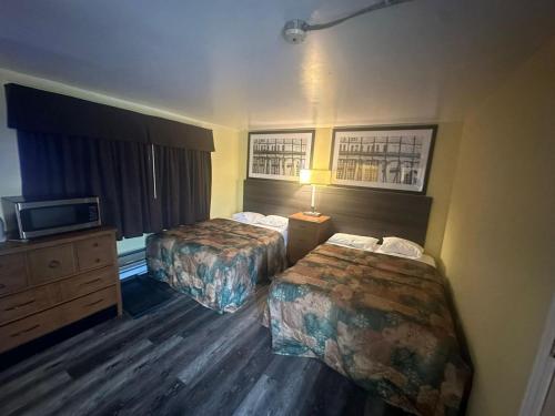 a hotel room with two beds and a television at Pine Ridge Motel in Timmins