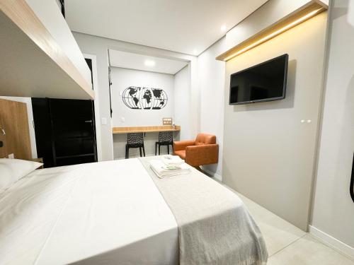 a bedroom with a large white bed and a television at Hotel São José in São José