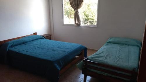 two beds in a room with a window at Alquiler temporario de casa amplia para 6 personas en San Clemente del Tuyú CONSULTAS AL MAIL lucasguarra arroba h o t m a i l punto com in San Clemente del Tuyú