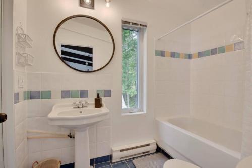 Un baño blanco con lavabo y espejo. en Cottage with water view and hot tub - Le pin blanc, en Baie-Saint-Paul