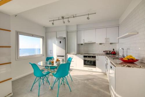 a kitchen with a table and blue chairs at Limassol Molos Hawaii Royal - Front-line 2 bedroom in Limassol