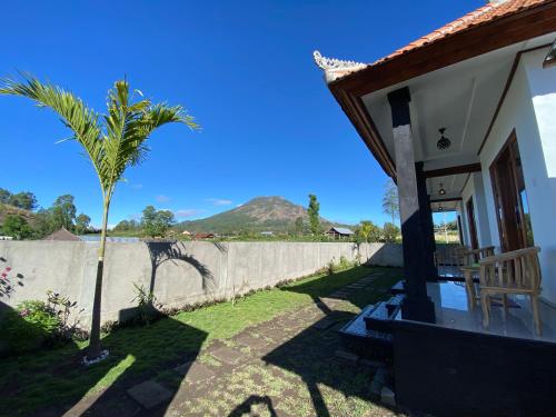 une maison avec un palmier et une clôture dans l'établissement Batur Volcano Cottage, à Kubupenlokan