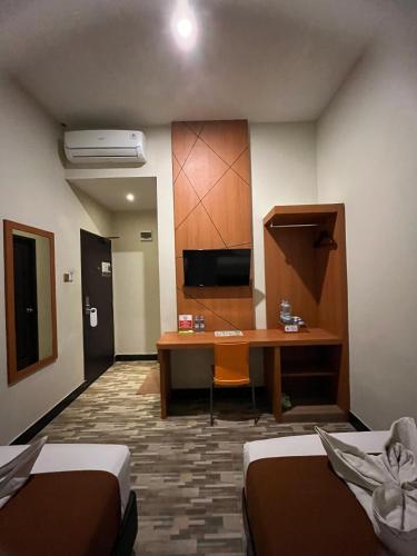a room with a desk and a room with two beds at Bless Hotels in Sintang