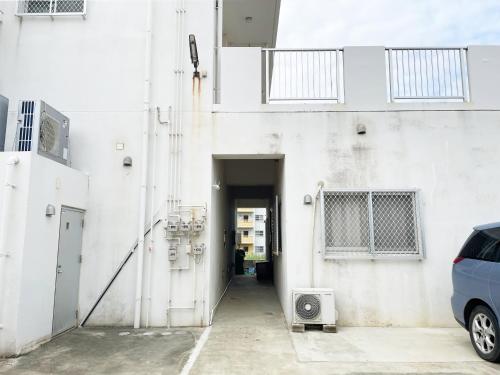 a white building with a car parked in a parking lot at アイコニー in Miyako Island