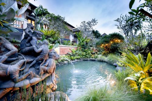 a fountain in a garden with a pond at Anumana Village Ubud in Ubud