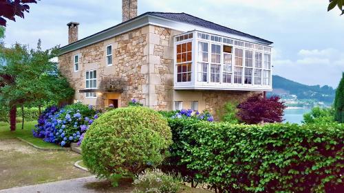 a large stone house with bushes and flowers at The Cliffs - A Pedrinha in Viveiro