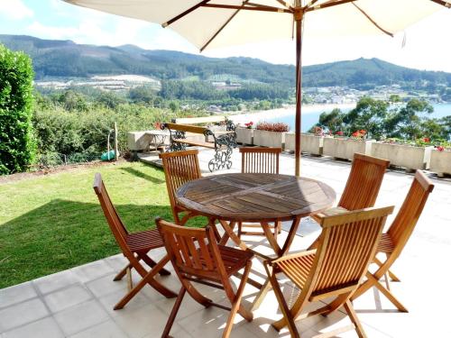 a wooden table and chairs with an umbrella on a patio at The Cliffs - A Pedrinha in Viveiro