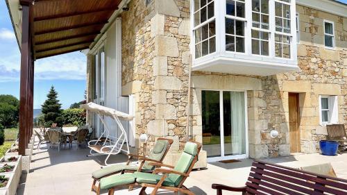 a patio with rocking chairs and a stone building at The Cliffs - A Pedrinha in Viveiro