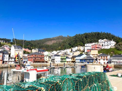 a boat is docked in a harbor with a town at The Cliffs - A Pedrinha in Viveiro