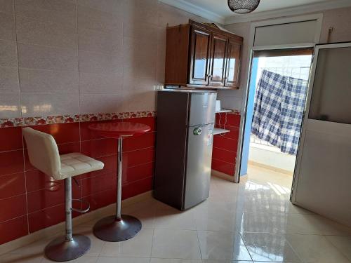 a kitchen with a refrigerator and a stool in it at شقة مفروشة سلوان ليلى in Selouane