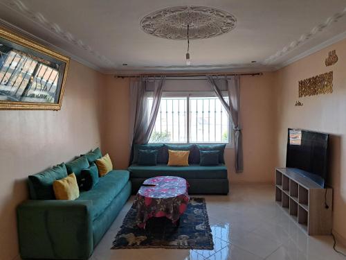 a living room with a green couch and a table at شقة مفروشة سلوان ليلى in Selouane