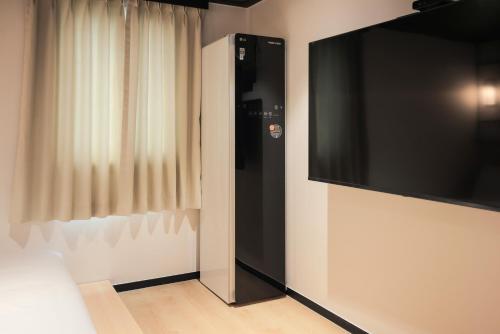 a flat screen tv on a wall next to a curtain at Mitasuya Ryokan Hotel Gumi by AanK in Gumi