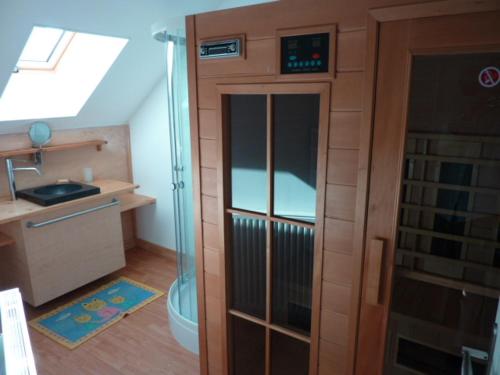 La petite salle de bains est pourvue d'une douche et d'une porte en verre. dans l'établissement Les Gîtes Du Vieux Frêne, à Longavesnes