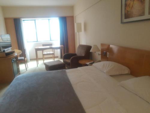 a hotel room with a bed and a living room at Hotel Alphaville Apto 909 in Barueri