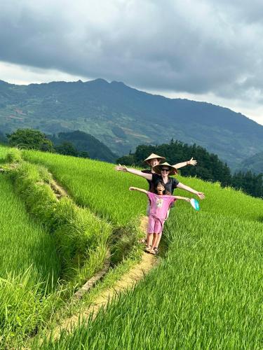 a woman and a child walking through a field at Bac Ha Lodge Retreat in Bắc Hà
