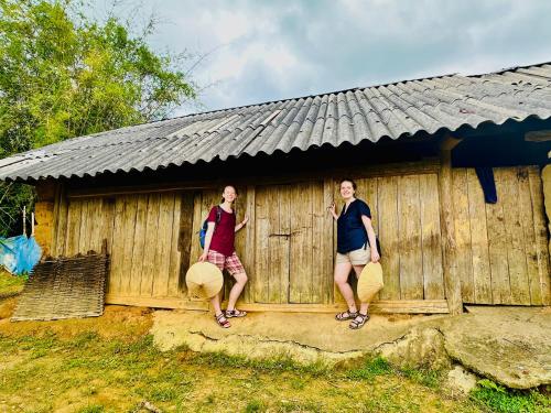 two women standing in front of a wooden building at Bac Ha Lodge Retreat in Bắc Hà