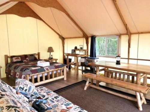 Zimmer mit einem Bett und Tischen in einem Zelt in der Unterkunft Howling Wolf Resort in Seward