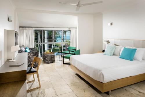 a bedroom with a large bed and a living room at Mangrove Hotel in Broome