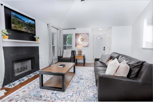 a living room with a black leather couch and a fireplace at Cozy, Round Rock Retreat, Modern, Sleeps 10 in Round Rock