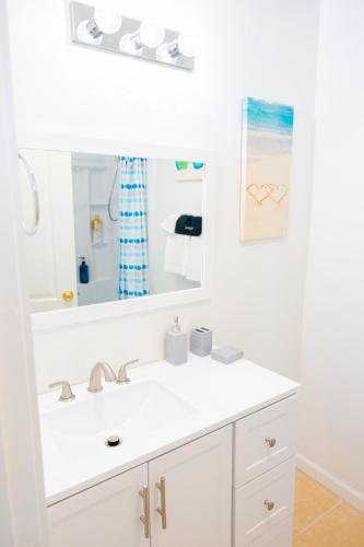 a white bathroom with a sink and a mirror at Charming Cute Home in Bakersfield