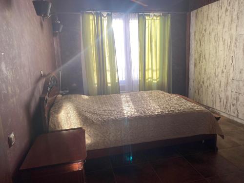 a bedroom with a bed and a window with yellow curtains at Stefania's house in Agia Effimia
