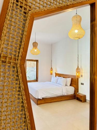 ein Schlafzimmer mit einem Bett und zwei Pendelleuchten in der Unterkunft Las Flores Lombok in Kuta Lombok