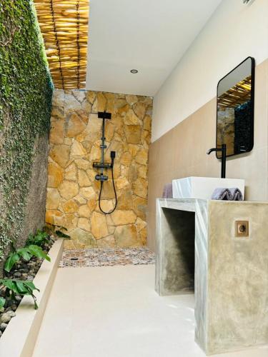 ein Badezimmer mit einem Waschbecken und einer Steinmauer in der Unterkunft Las Flores Lombok in Kuta Lombok
