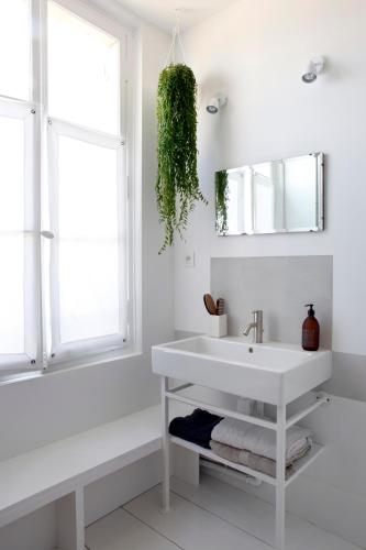 a white bathroom with a sink and a mirror at La Maison & L'atelier in Neuilly-en-Thelle