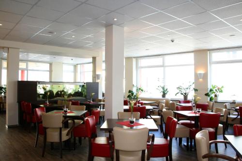 a dining room with tables and chairs and windows at home Hotel in Wilhelmshaven