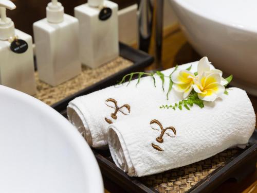 a bathroom with towels with numbers and a flower on them at Baan Puri - SHA Extra Plus in Lipa Noi