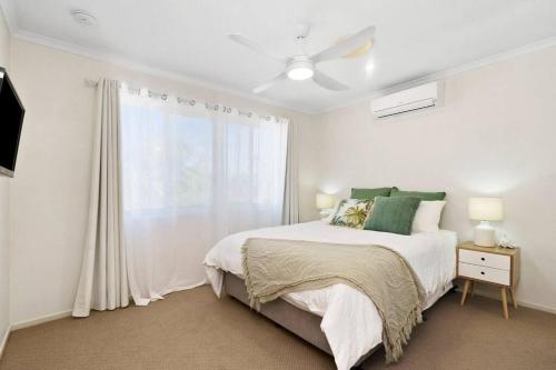a white bedroom with a bed and a window at Fully airconditioned, pet friendly, 5mins to beach in Caloundra