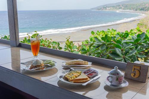 a table with two plates of food and a view of the beach at Manta Cottages with Sea View in Nusa Penida