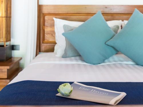 a book sitting on top of a bed with blue pillows at Baan Puri - SHA Extra Plus in Lipa Noi