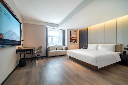 a bedroom with a large white bed and a desk at Atour Hotel Changchun Jingyuetan Park Jingyue Street in Changchun