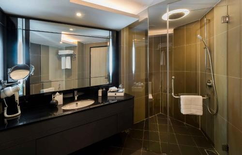 a bathroom with a sink and a shower with a mirror at The Kuala Lumpur Journal Hotel in Kuala Lumpur