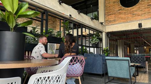 a man and woman sitting at a table in a restaurant at Los Patios Cool Living in Medellín